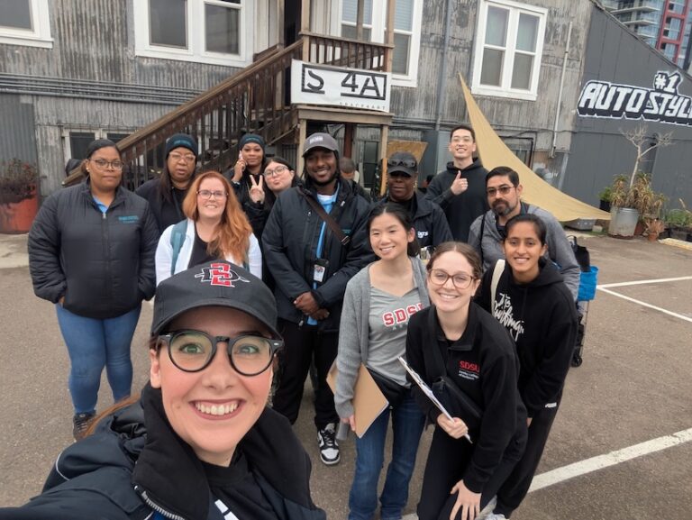 A group of men and women posing for a photo outside