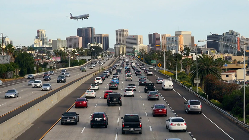 A busy city freeway with an airplane flying overhead