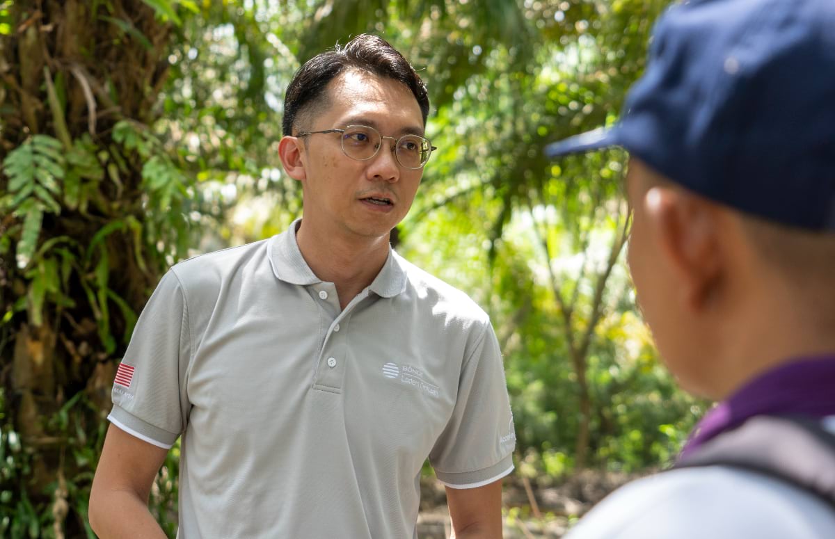 Bunge representative in conversation with a farmer against a lush green tropical background.