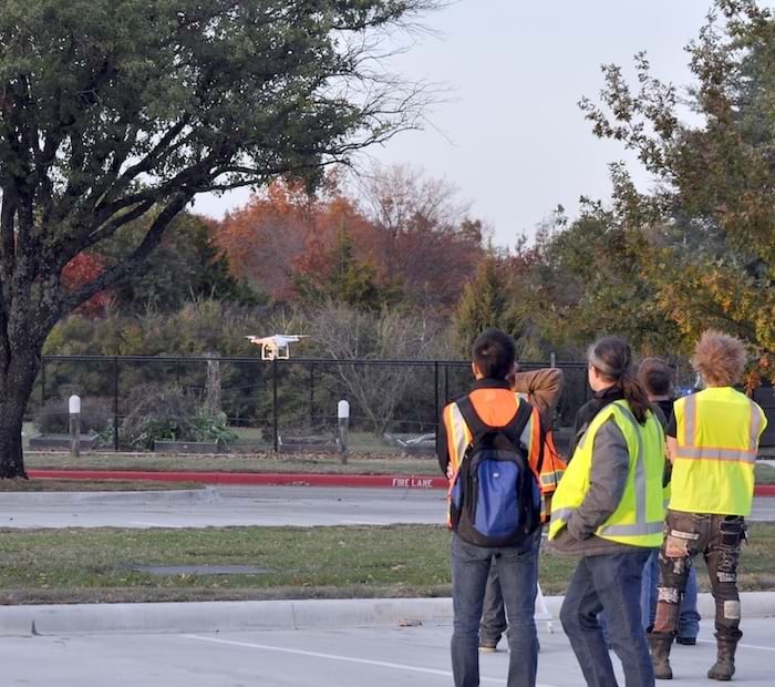 A group of students outdoors flying a drone