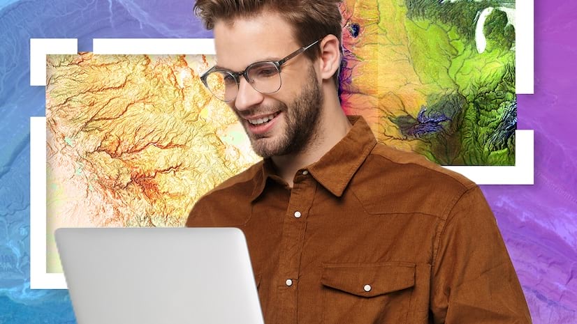A smiling young man with glasses working on a laptop