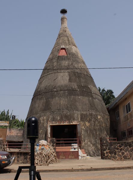 Photo of a large gray conical structure with an open doorway, taken from across the street. A black scanning device in the foreground is pointed at the structure.