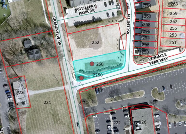 Overhead satellite image of a parking lot and multiple buildings, overlaid with red lines that indicate the boundaries between lots. A transparent blue polygon indicates the area that is not intended for housing development.