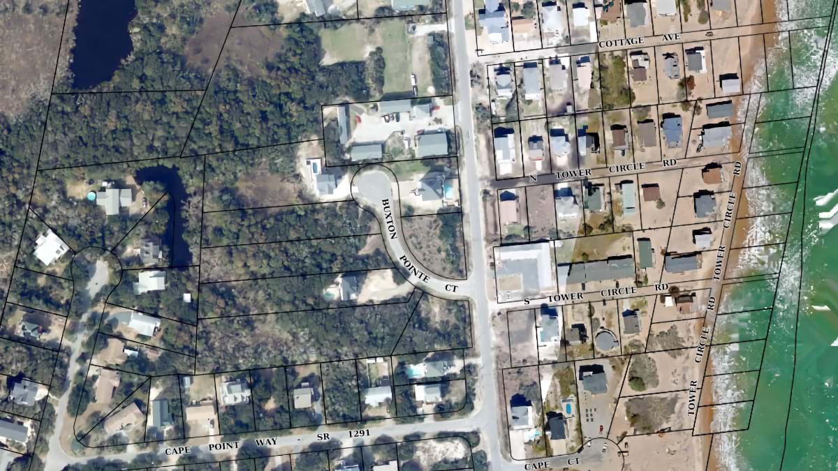 Aerial parcel map of Buxton, NC showing residential lots along the oceanfront with bare, vacant parcels near the water's edge.