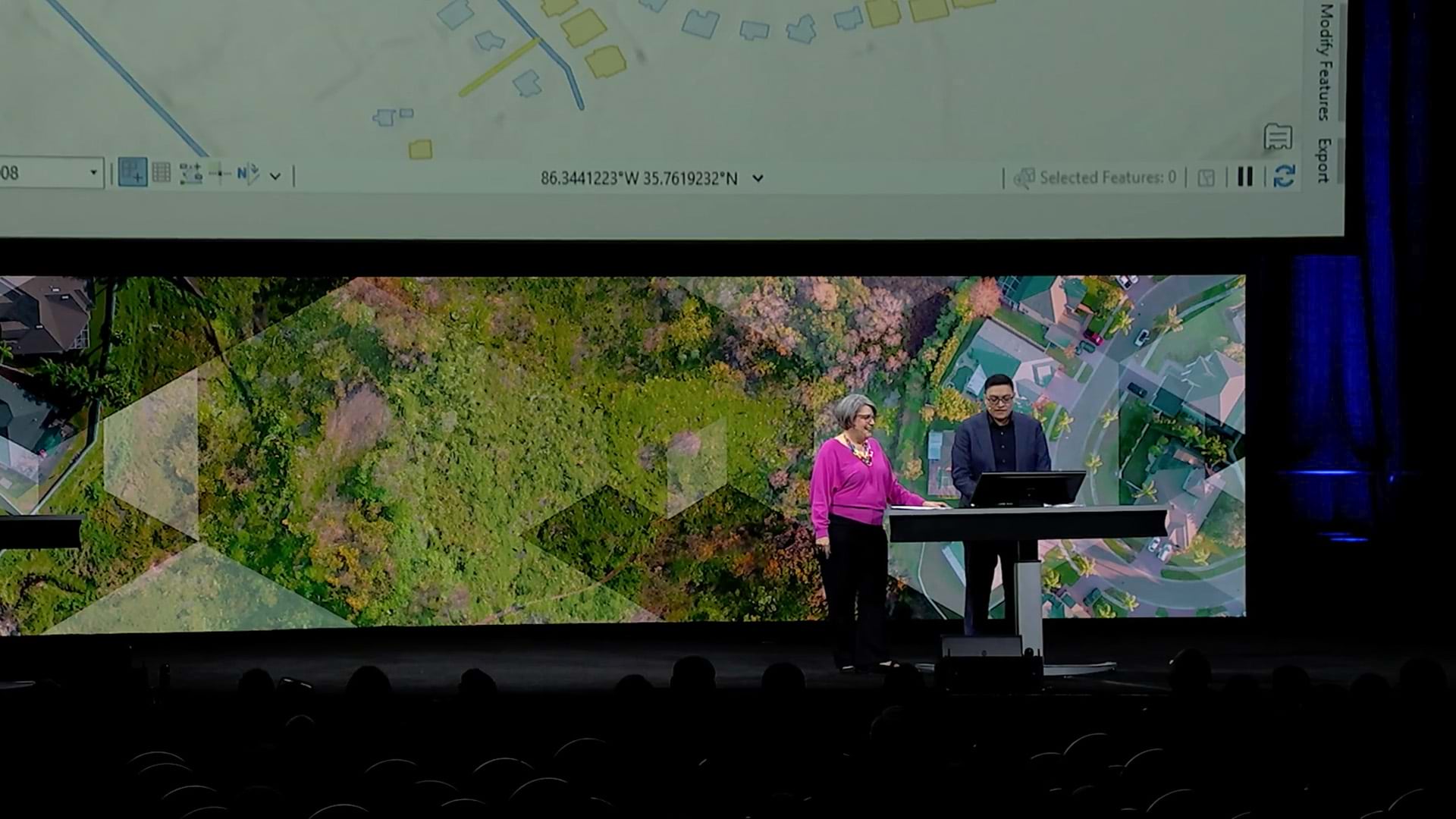Two people standing on a stage presenting to an audience