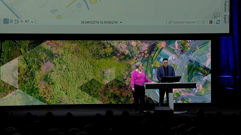 Two people standing on a stage presenting to an audience