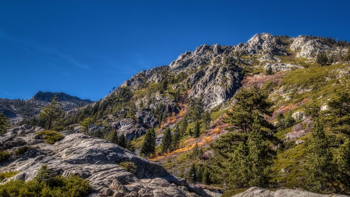 Rocky mountain ridge with scattered pines under a clear blue sky in Eldorado National Forest.