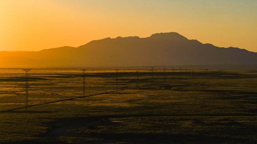 A large transmission line set against a sunset and mountains