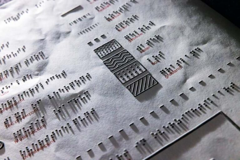 A black and white braille legend listing various textures for features such as water and grassland is photographed at an angle to show features in relief.
