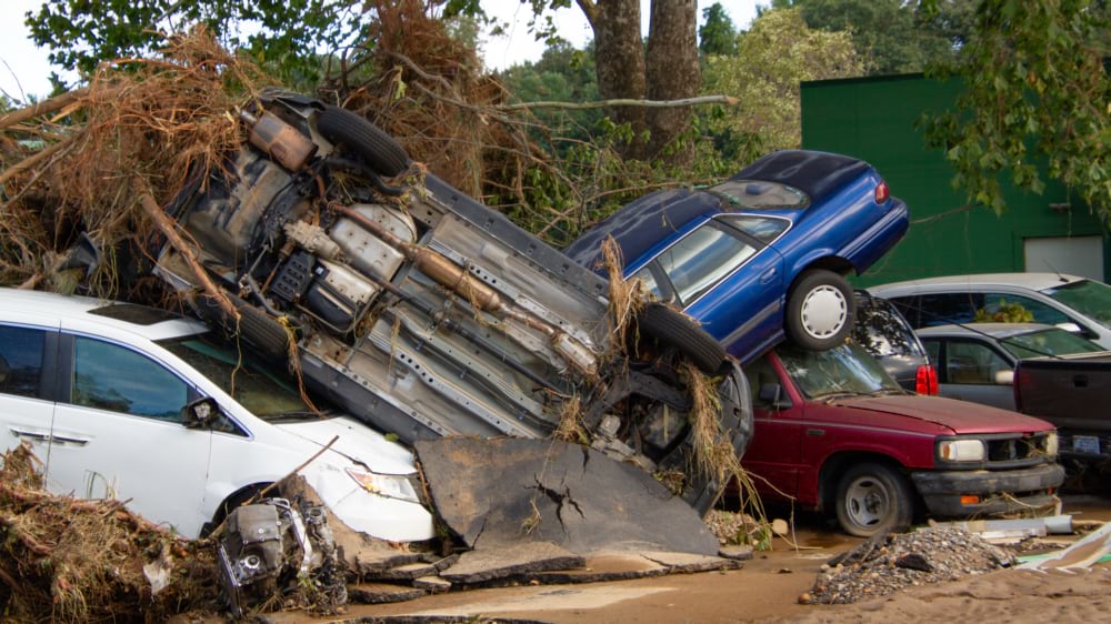 Wrecked and overturned cars piled together after flood damage from Hurricane Helene.