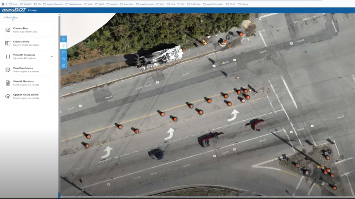 Overhead drone orthomosaic in ArcGIS Hub showing an intersection with road marking equipment, orange cones, and freshly painted pavement markings.