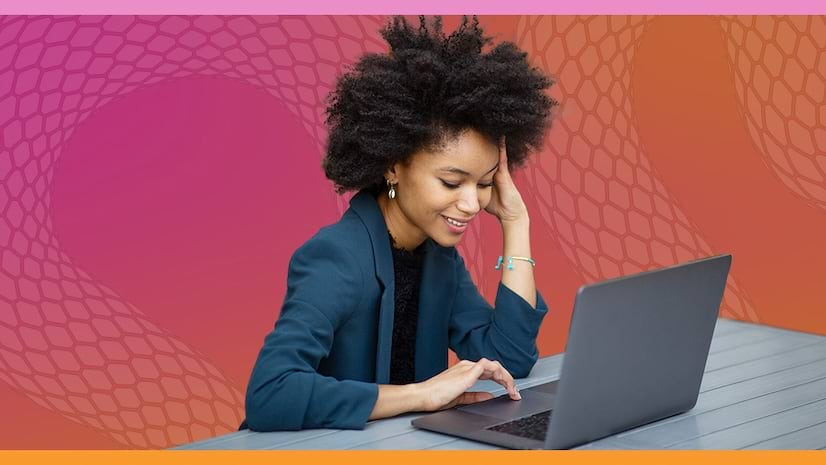 A smiling young woman working on a laptop set against a pink and orange abstract background