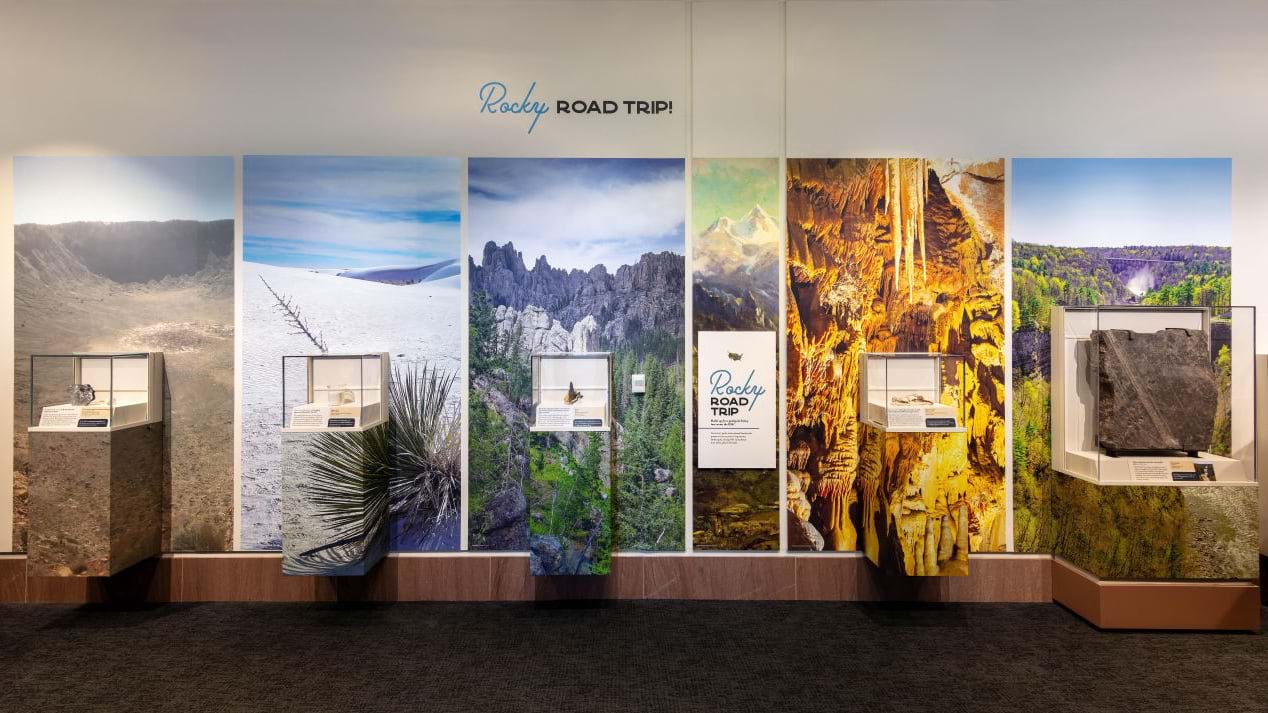 A gallery wall shows six large landscape photographs, each paired with a small mineral case.