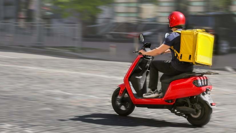 A food delivery person on a moped signifies the delivery services offered by UK retailer Co-op