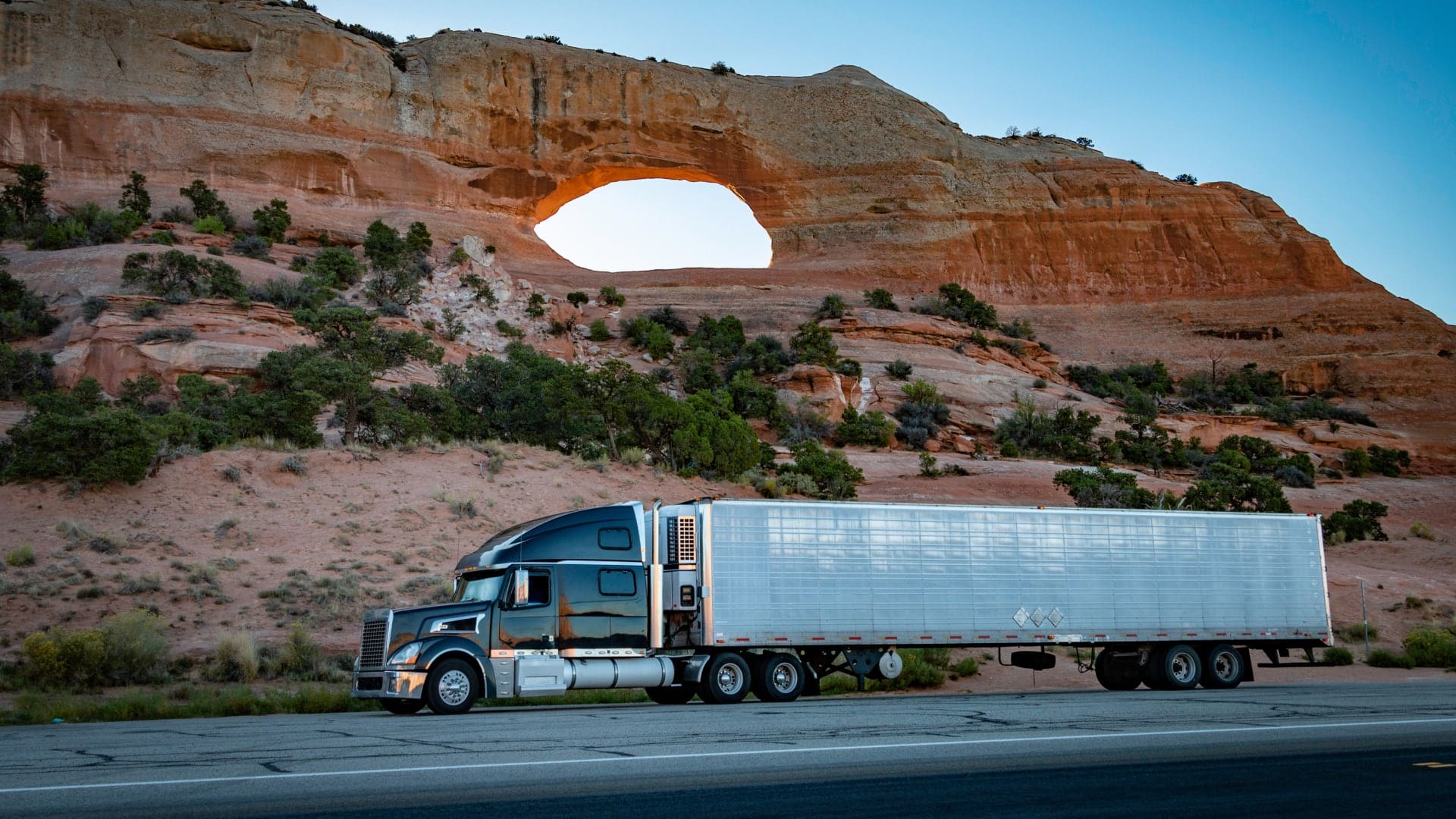 An 18-wheeler parked near a red-rock arch suggests the responsibilities of fleet managers