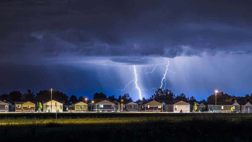 Dark storm clouds and lightning over a suburban neighborhood