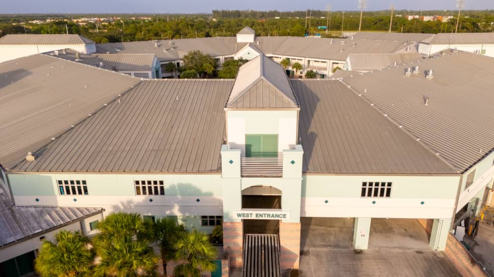 Aerial view of a high school's marked west entrance and rooftop.