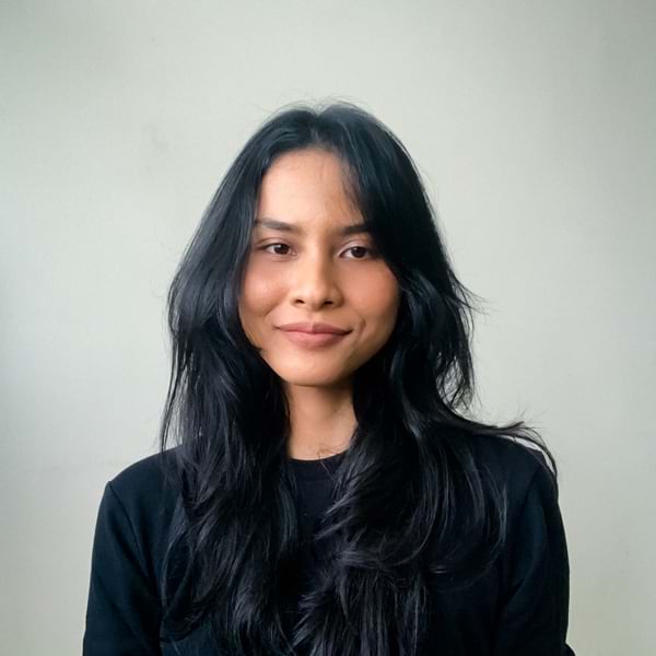 Headshot of a woman with long, wavy black hair, wearing a black shirt and smiling softly at the camera.