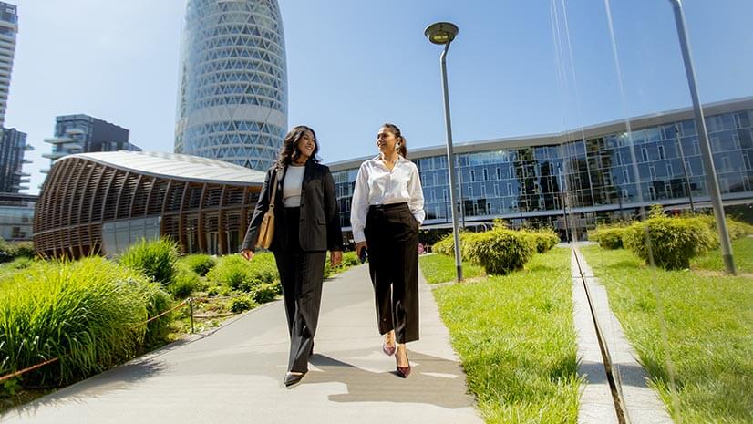 Two office workers walk through green space