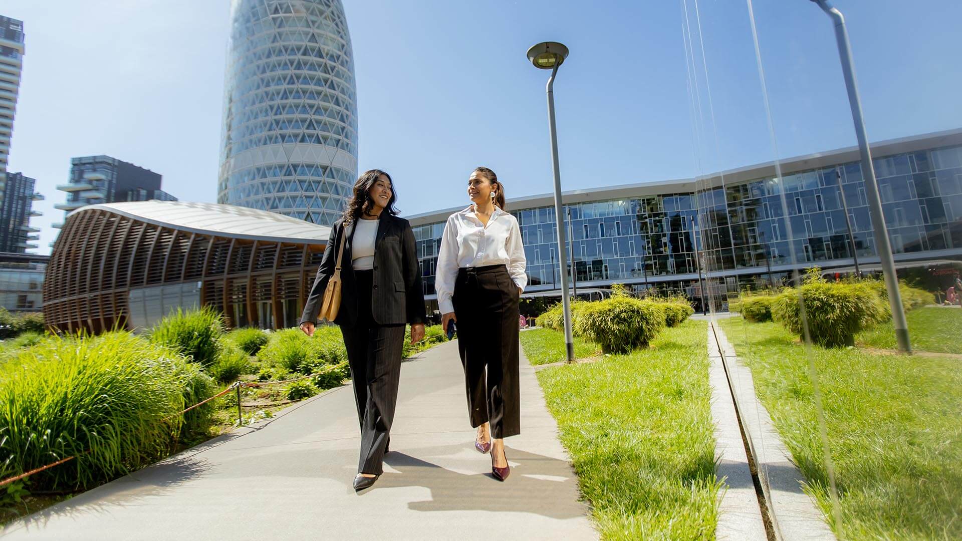 Two office workers walk through green space