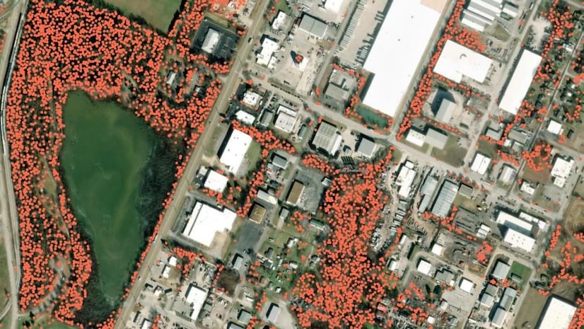 An aerial image of a town with buildings and roads with scattered red data points