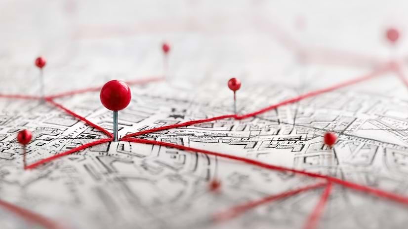 Pins with red dots on top connected by red yarn on a map