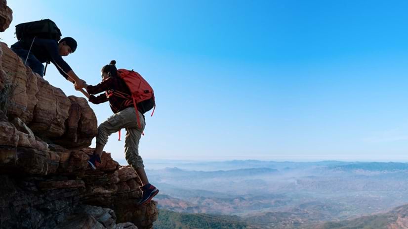 Two mountain climbers helping one another signifies how GIS teams empower colleagues