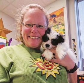 Kelly Adams wears her GIS shirt and gives the office therapy pup, a quick snuggle