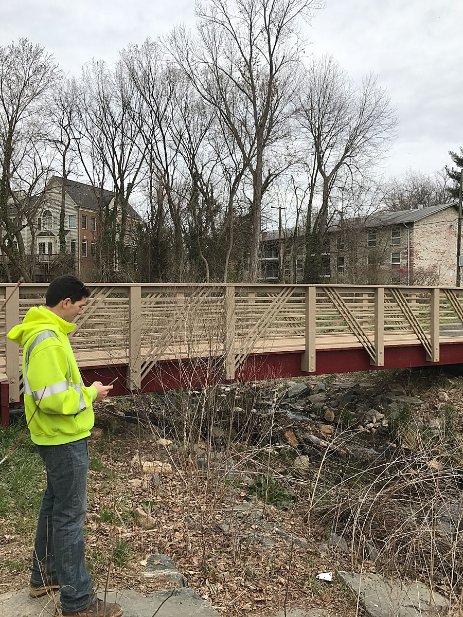 A city employee uses Collector for ArcGIS on a mobile device to collect information about a bridge in Falls Church. Photo by Andrew Peters.