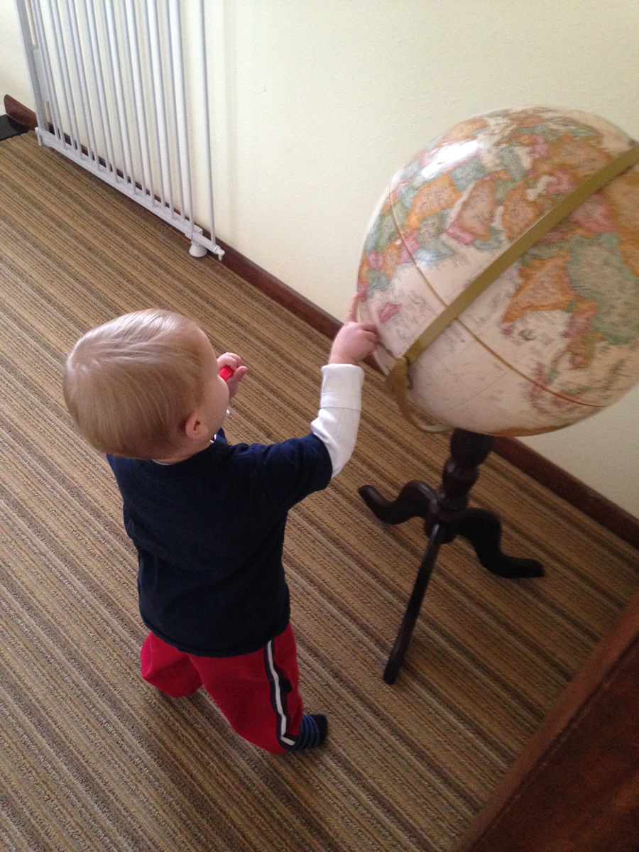 While brushing his teeth, Miller points to countries he has learned about on a globe.