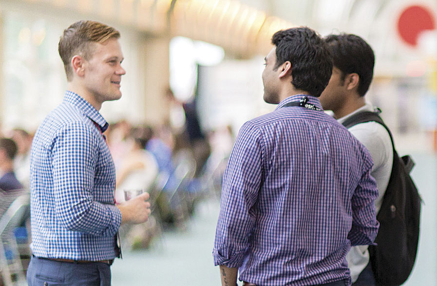 Esri account manager John Dombzalski (left), who helped launch the Young Professionals Network, speaks with young GIS professionals at a social event.