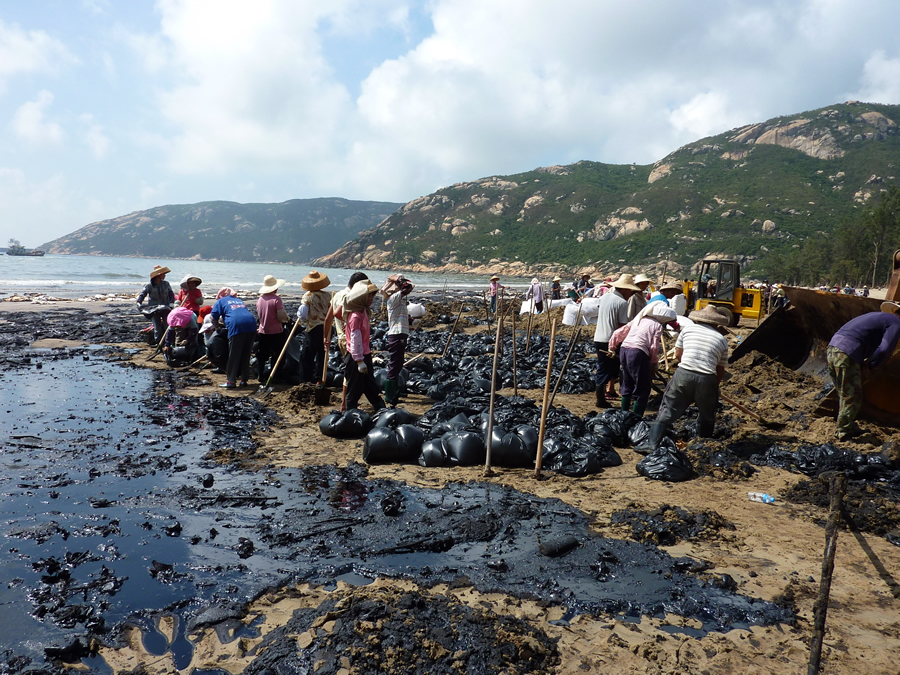 People clean the beaches in a China coastal community after an oil tanker spill.