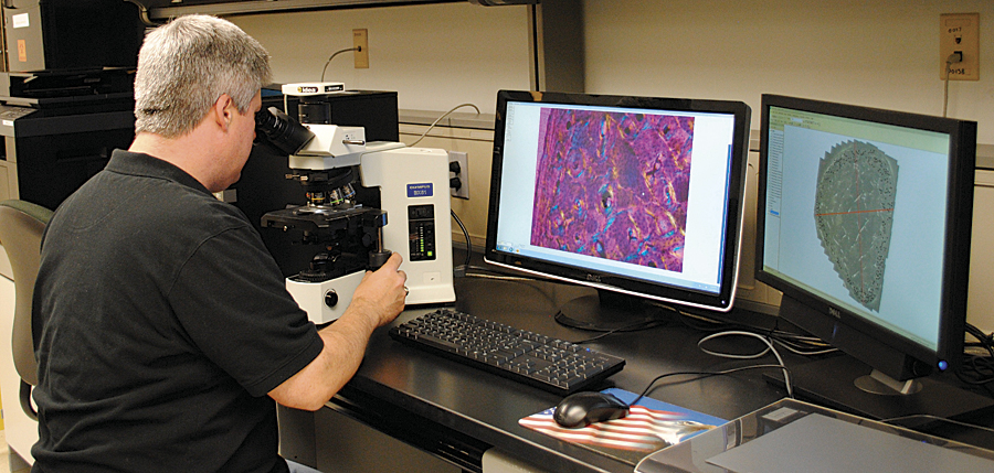 The computer monitor (right) shows ArcGIS 10 running with a bone map displayed. The left image is a bone cross-section under magnification. (Photo courtesy of David Rose, pictured.)