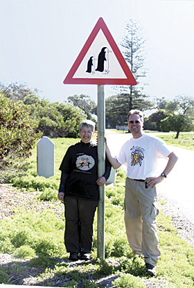 Kathryn Scott and Brian Hall, GIS analysts posed with their Esri T-shirts at a penguin crossing on Robben Island