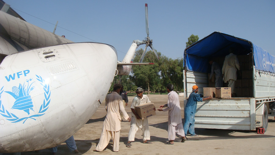 Aid workers load energy biscuits into a helicopter.