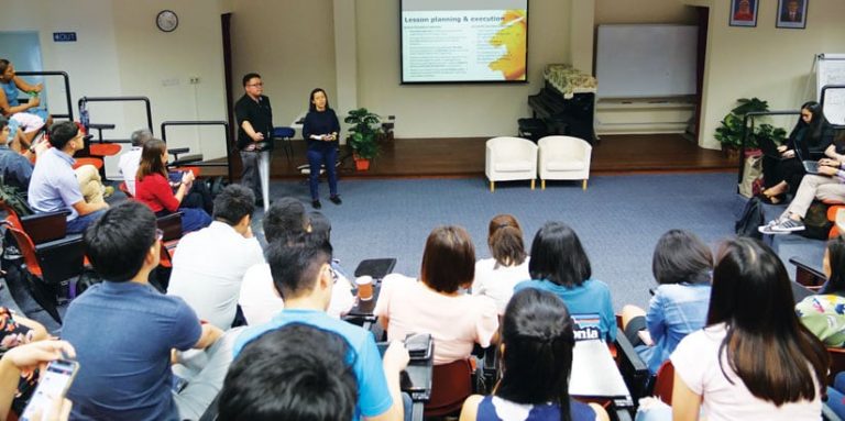 Two teachers giving a presentation about MOE-EduGIS to a roomful of attendees