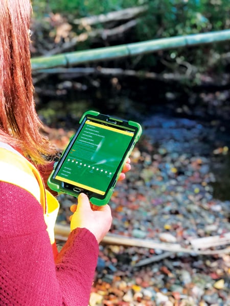 A photo of a woman using Survey123 for ArcGIS on a tablet