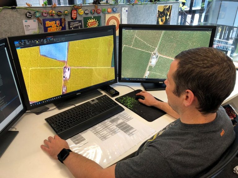 A man looking at aerial imagery on two computer screens