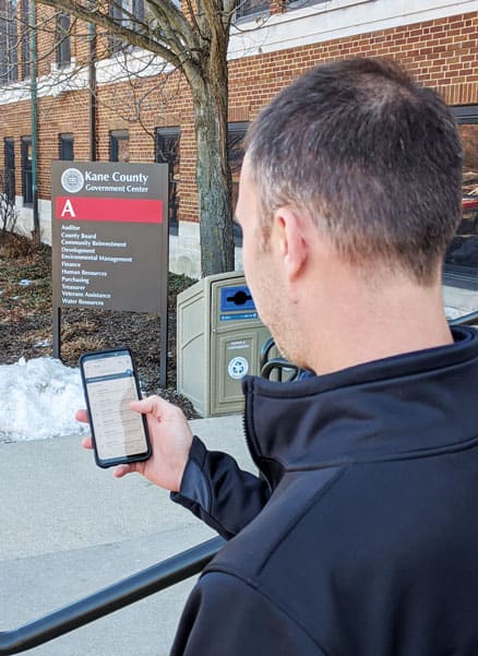 Photo of a man in front of a government building checking his phone