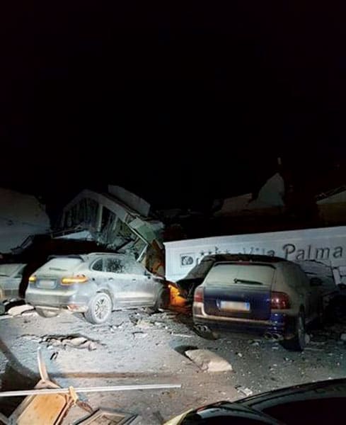Photo of two cars destroyed by a fallen building Photo of two cars destroyed by a fallen building