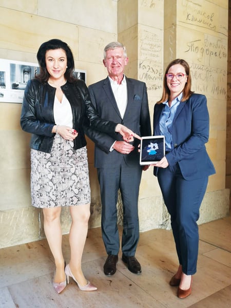 A photo of three people, two women and a man, holding a mobile device with a map on it