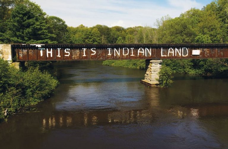 A train bridge crossing the Garden River FirNation reserve with “This is Indian Land” graffitied on the side