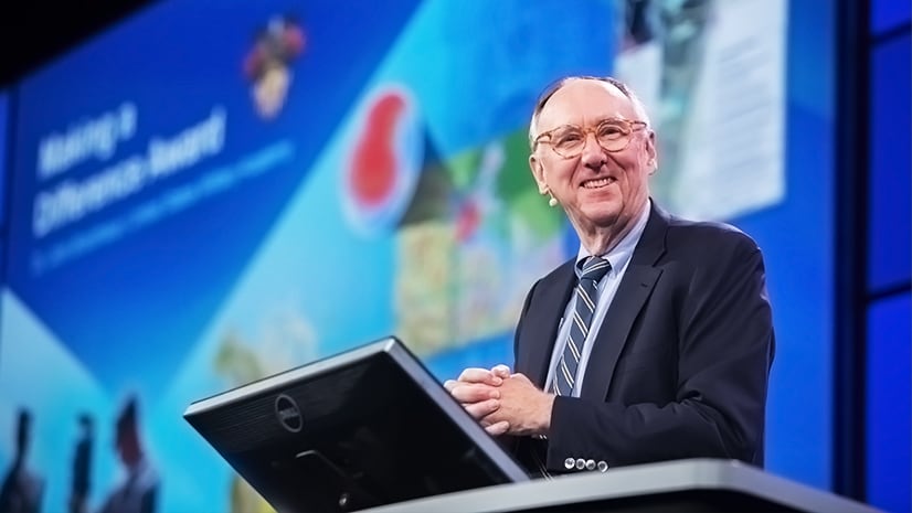 Esri president Jack Dangermond smiling on stage at a conference