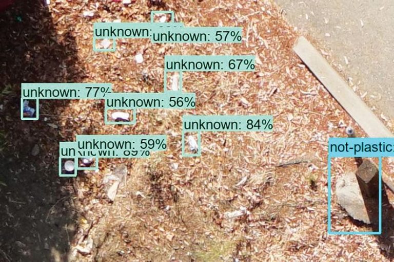 Trash items detected in a land fill and marked by machine-learning with a turquoise rectangle stating “unknown” with a percentage