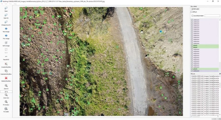 Drone imagery of a road, grass, and dirt, and green markers indicating where trash is located