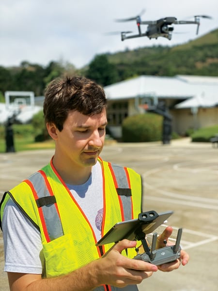 Pete Kauhanen, GIS manager and UAS pilot at SFEI, wearing a bright yellow and orange safety jacket, flying a drone