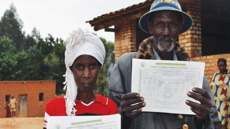 Two Rwandans holding up titles and certifications of land