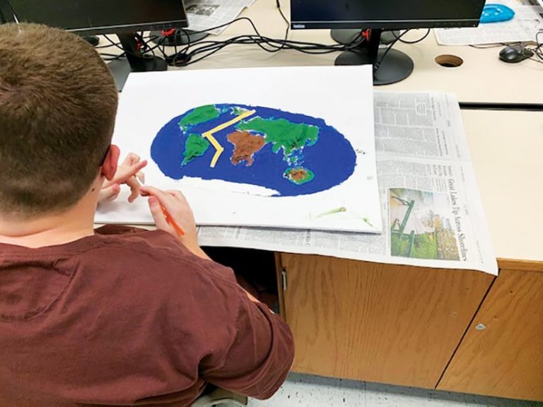 Student sitting at a desk working on a physical 3D map