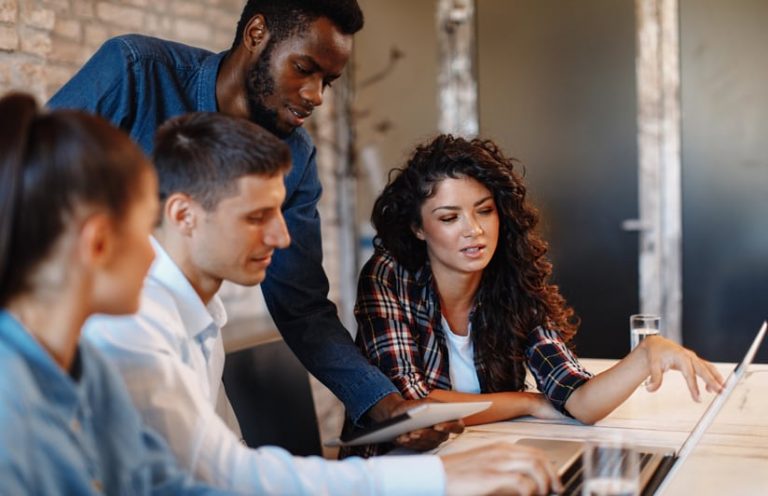 Four people working on a laptop together