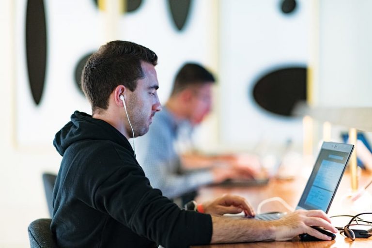 A man with headphones in working at a computer